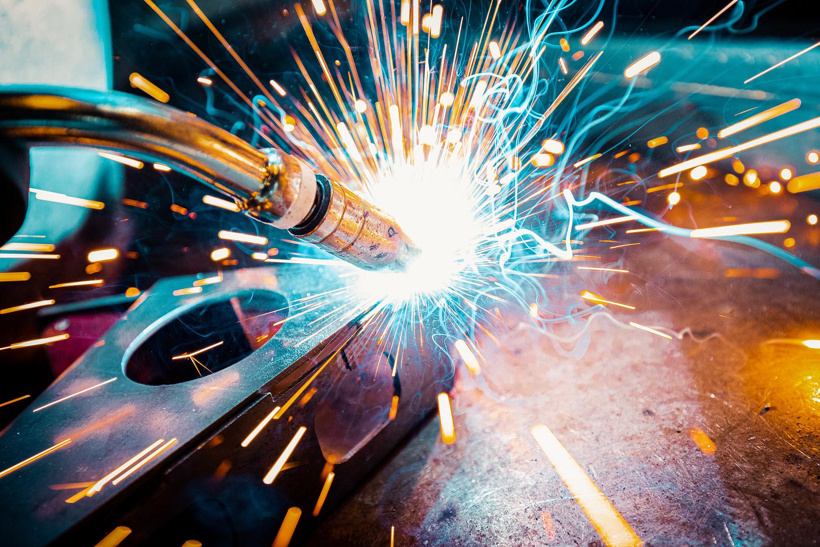 Sparks flying from a robotic arc weld during in-house fabrication at Robot World Automation