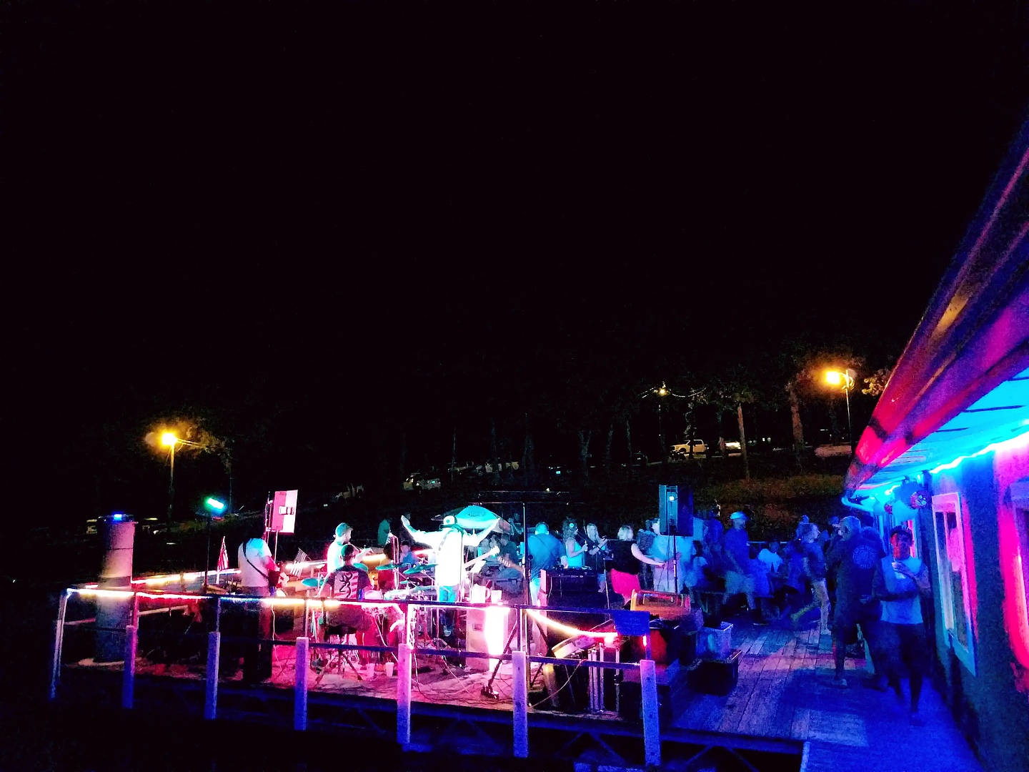 Live band and crowd on the No Wake Oasis patio at night under colorful string lights