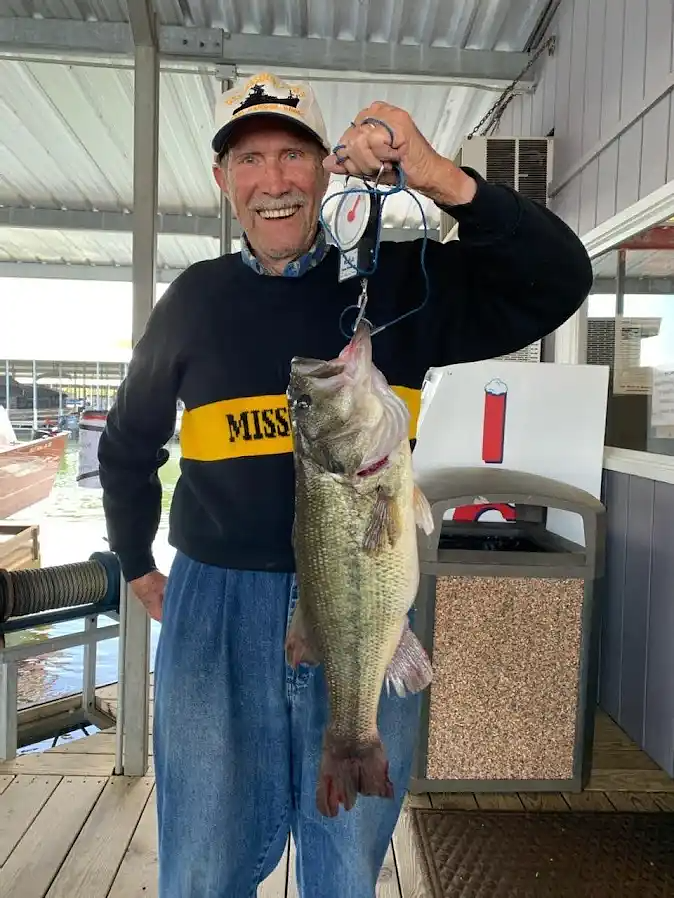 An angler holding up a large bass catch at the marina