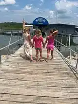 Three children holding hands and playing on the marina dock