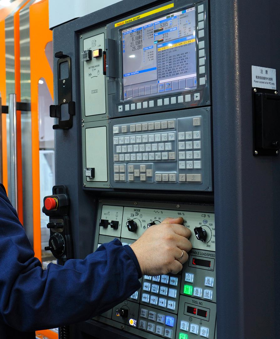 Technician adjusting settings on a CNC machine control panel