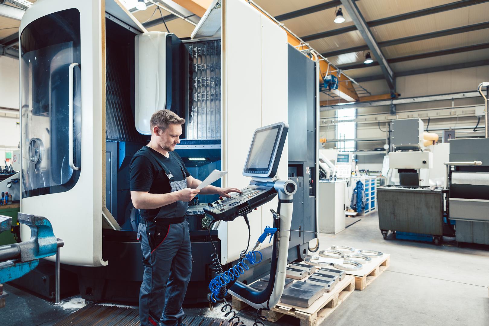 Operator working at a CNC machine control on a plant floor