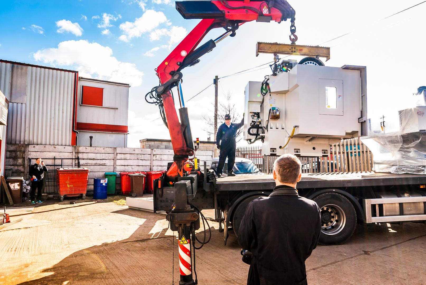 Crane lifting a machine onto a truck for a move