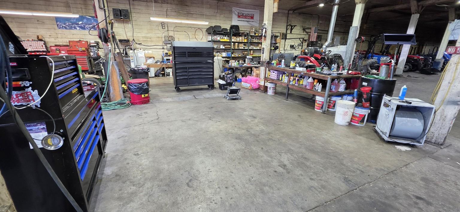 TractorCo service technician working on a compact tractor in the shop