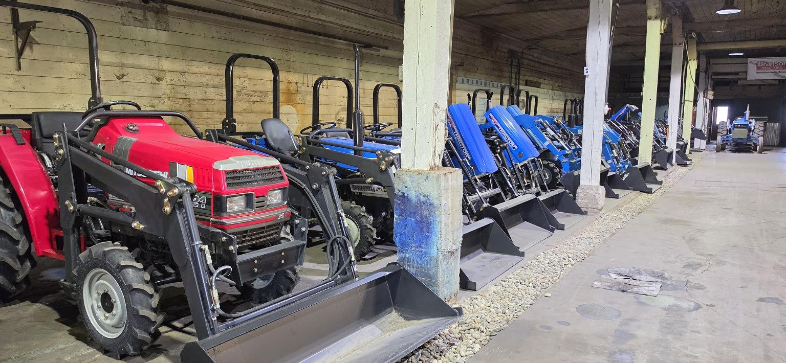 Row of pre-owned compact tractors at TractorCo