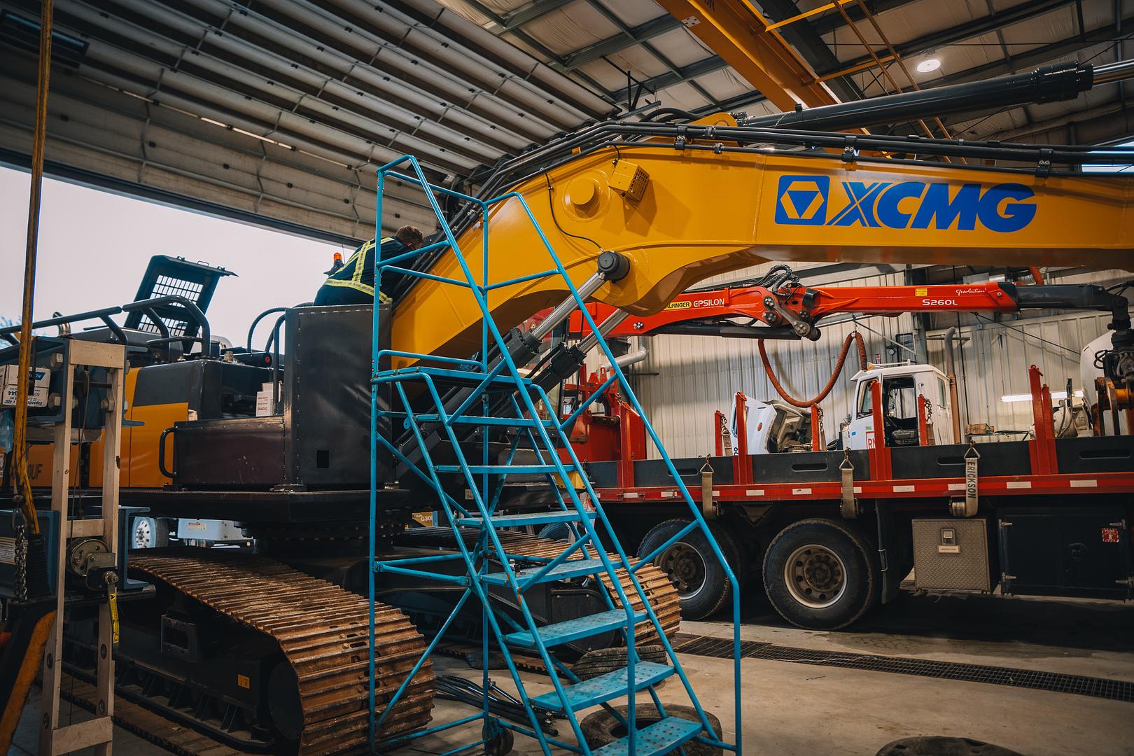 Excavator on a trailer deck inside the Motion Machinery inspection bay