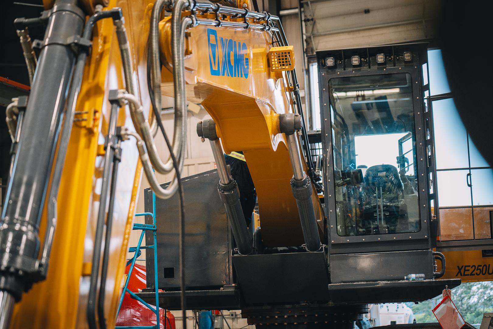 Close view of excavator boom cylinders and hydraulic lines during an inspection
