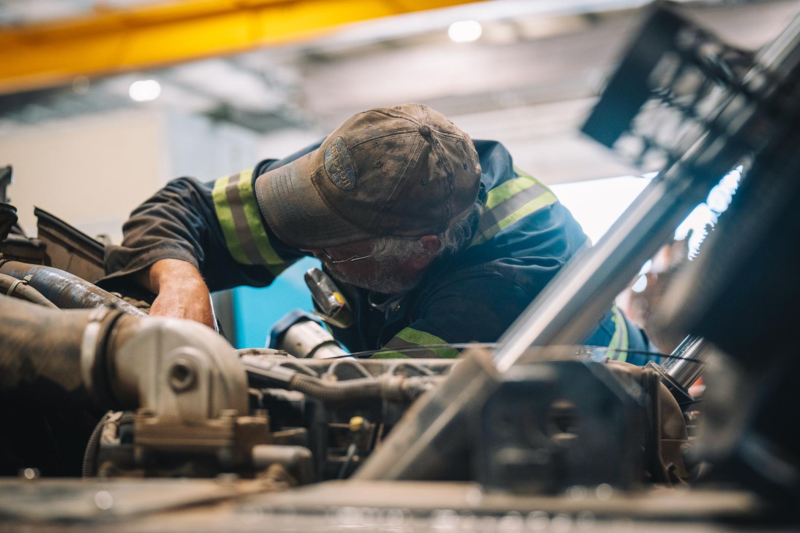 Motion Machinery technician working in a truck engine bay with the hood raised in the shop