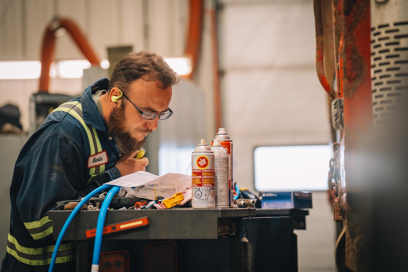 Motion Machinery technician reviewing an inspection report at the bench beside a machine