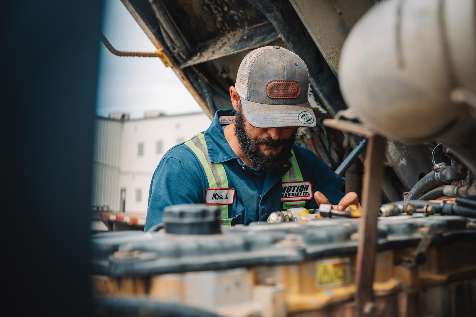 Certified Motion Machinery technician in branded coveralls servicing an engine