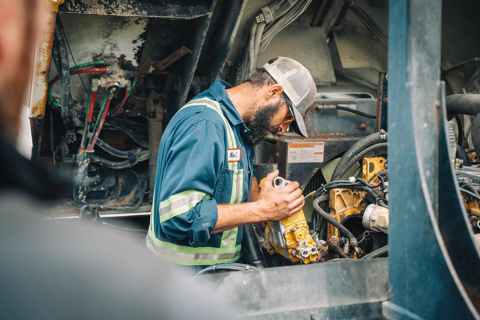 Certified technician working inside the engine bay of a heavy truck on a service call