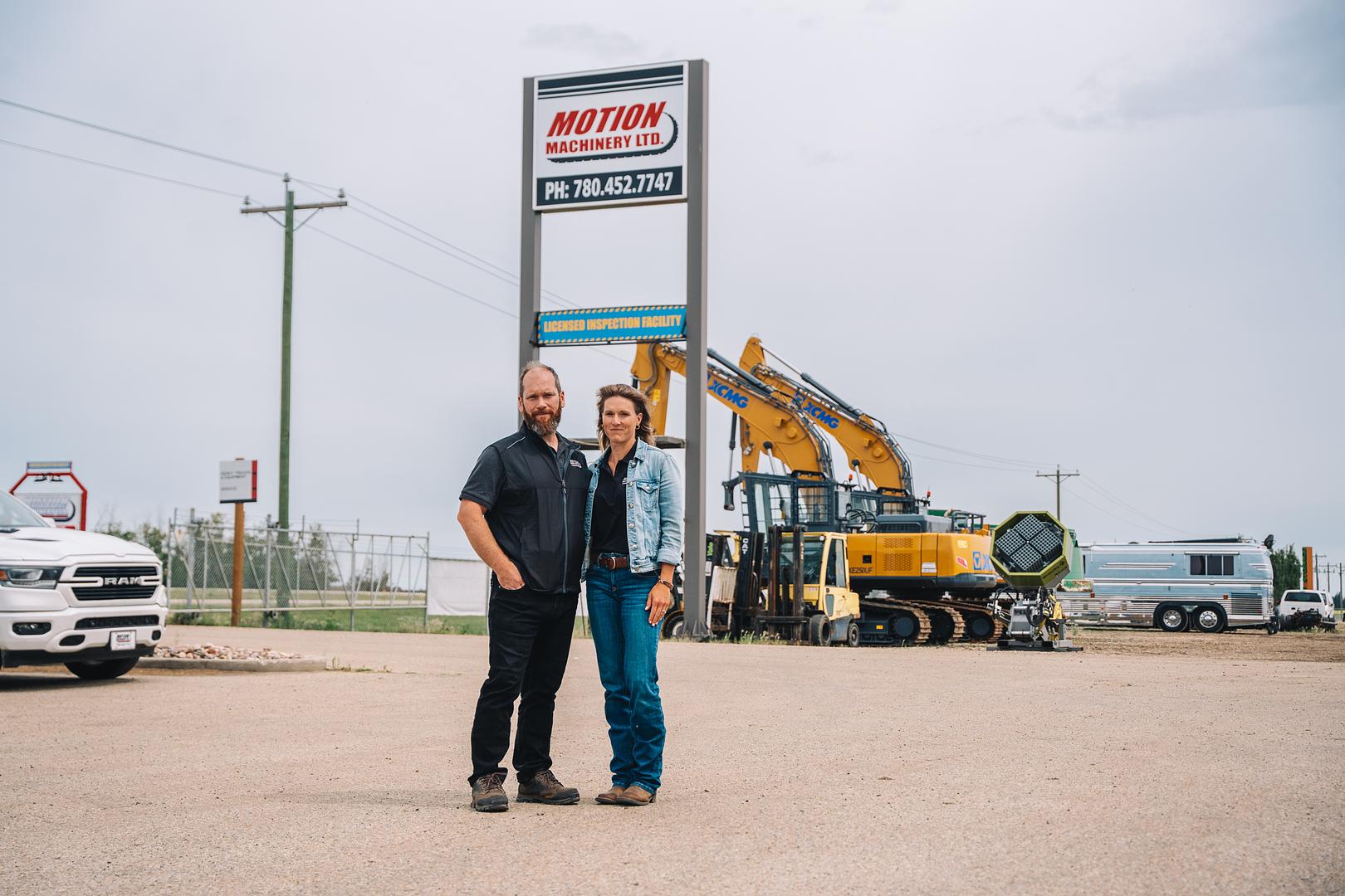Two members of the Motion Machinery team standing under the shop sign in Stony Plain, Alberta