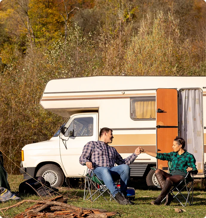Couple relaxing beside their camper van at a campsite
