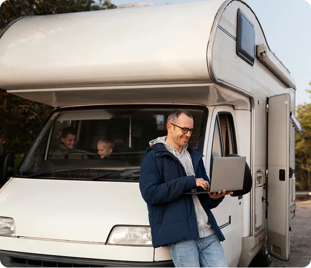 RV owner working on a laptop beside his motorhome