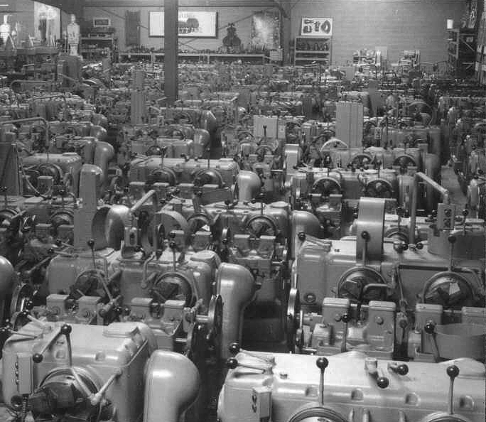 A black and white photo of machines packed into the shop